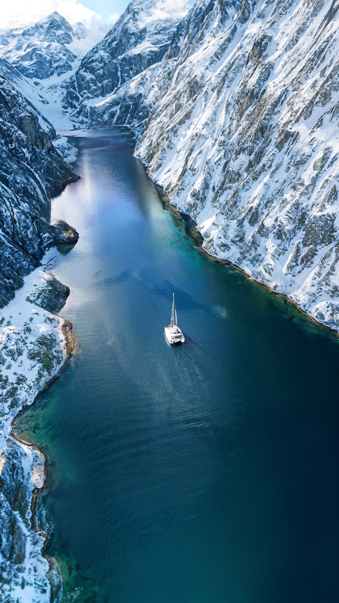 Aerial drone view of the catamaran in a snowy Arctic fjord