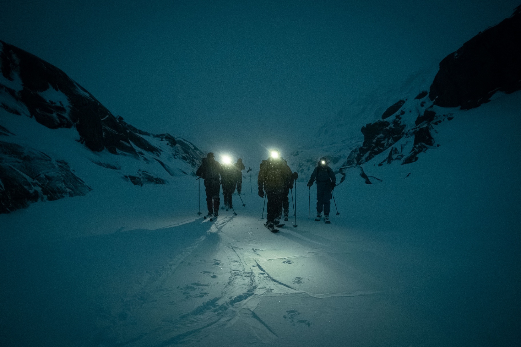 Ski-tourers ascending under headlamps at night