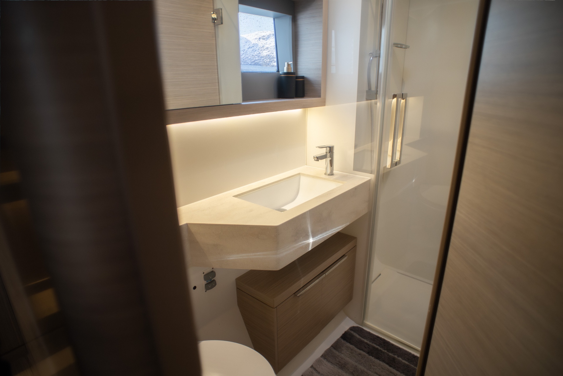 Guest head with stone vanity, mirrored cabinet and view to the fjord